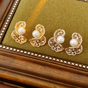 Detail van vergulde bloemenoorbellen met witte parel en fonkelende zirkoon accenten