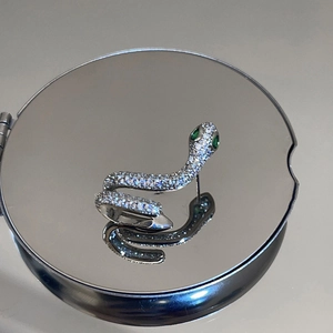 Vue détaillée de boucles d'oreilles serpent en argent avec yeux en zircon vert sur miroir