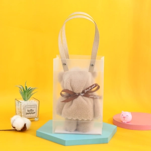 Macro detail of brown bear-shaped microfiber towel in clear PVC gift bag with ribbon