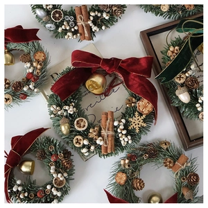 Flat lay of mini Christmas wreaths with pine needles, cinnamon sticks and pinecones
