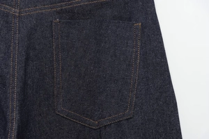 Macro view of indigo denim jeans back pocket with orange double-needle stitching detail