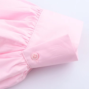 Detail shot of pleated pink poplin shirt cuffs with matching resin button and fine stitching
