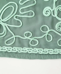 Detailed macro view of mint green rope embroidery on bean green elegant fabric