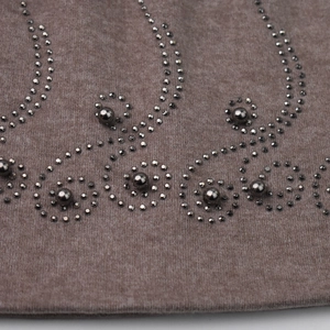 Détail de maille marron avec strass argentés et broderies de perles en motif floral