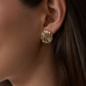 Polished 18k gold plated stainless steel spiral swirl stud earrings worn by a model