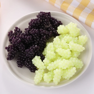 Close-up of realistic mini resin grape and mulberry models in a white ceramic dish