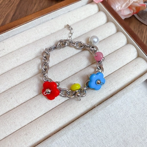Detail of a floral chain bracelet with colorful charms inside a beige velvet jewelry box