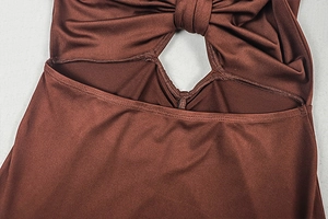 Detail view of the twist-knot bust and waist cutout design on a red-brown dress