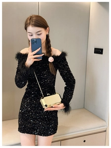 Detail of model holding a gold geometric clutch bag with black sequin feather dress