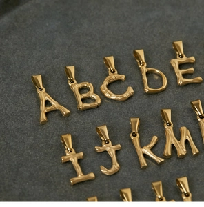 Macro detail of 18K gold plated bamboo texture alphabet pendants in stainless steel