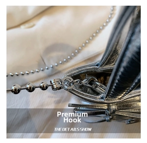 Close-up of premium metal lobster clasp and ball chain on silver textured handbag