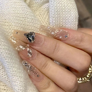 Macro detail of long coffin press-on nails with heart rhinestones and white pearls