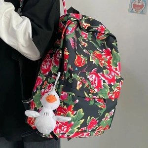 Detail of backpack with red floral patterns and a cute white duck plush keychain