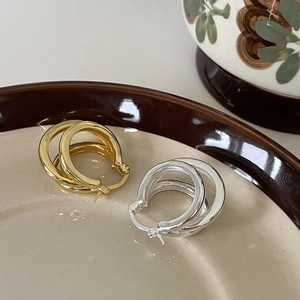 Elegant 925 sterling silver triple-hoop earrings in gold and silver finishes on a ceramic tray