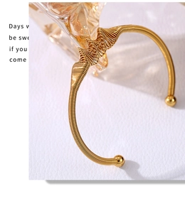 Detailed view of the intricate spiral wire weave and golden wave design on this open bangle