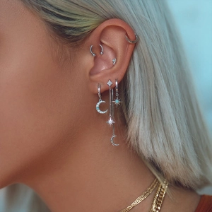 Close-up of S925 silver star and moon tassel chain earrings with blue stones on ear