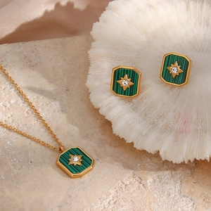 Detailed shot of retro gold necklace and earrings with green malachite and star motifs