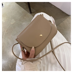 Detail of light brown leather crossbody bag with golden round snap button and thin strap