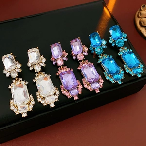 Detailed view of three pairs of vintage square crystal earrings in blue, purple, and clear