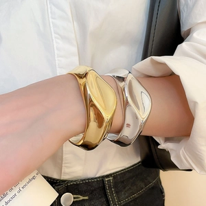 Detail of chunky irregular lava-style cuffs in gold and silver finish worn by a model