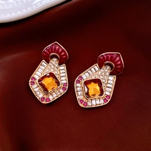 Close-up of vintage gold earrings with amber stone on red silk fabric background