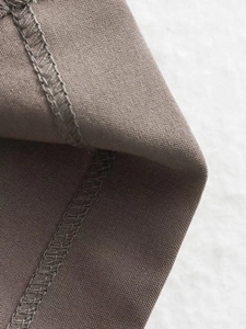 Macro shot of dark taupe fabric showing fine plain weave texture and overlock sewing detail