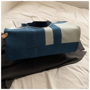 Detail of blue denim and beige canvas patchwork tote bag on white background