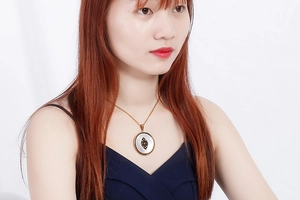 Detail of gold oval evil eye pendant with shell inlay on a delicate chain necklace