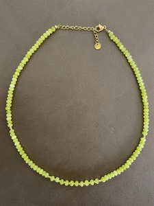 Detail von lindgrünen facettierten Perlen mit vergoldetem Karabinerverschluss und Kette
