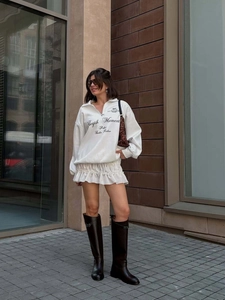 White quarter-zip sweatshirt with letter embroidery and pleated mini skirt outfit