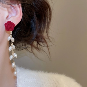 Close-up of red flocked flower earrings with dangling baroque pearl tassels on model