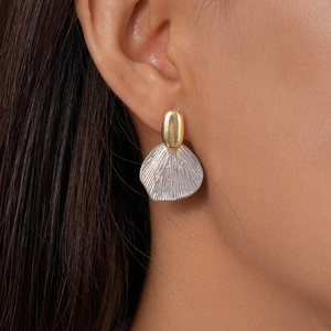 Detail shot of geometric mixed-metal earrings with gold oval and silver shell texture