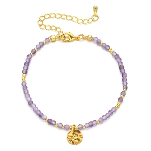 Close-up of purple stone beaded bracelet with gold accents and hammered metal pendant