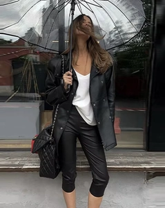 Detail shot of double-breasted PU leather jacket and pants in a city street setting