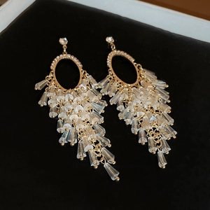 Detail of golden tassel earrings with crystal beads on black velvet jewelry box background