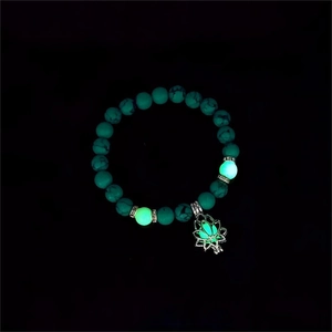 Close-up of luminous lotus charm and turquoise beads glowing in a dark setting