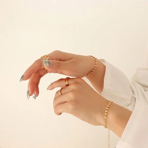 Minimalist gold plated stainless steel jewelry set with embossed charms on a model's hand