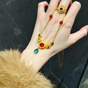 Ethnic gold jewelry set with red and blue resin stones on a necklace and matching ring