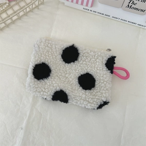 Detailed close-up of plush polka dot coin purse in cream white with soft lamb wool texture