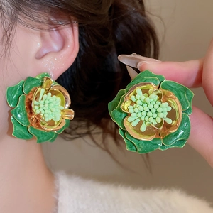 Vue macro détaillée de boucles d'oreilles fleurs 3D vertes avec bordure dorée