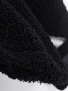 Detailed close-up of thick black faux shearling fabric with soft plush texture and warm fibers