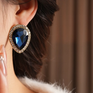 Détail de boucles d'oreilles vintage avec perle goutte bleue et bordure dorée diamantée