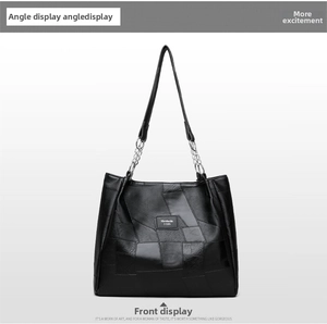 Detail of black patchwork leather tote bag with silver chain straps and logo plate
