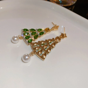 Close-up of golden Christmas tree earrings with green crystals and pearl drop