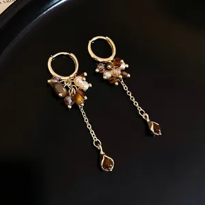 Elegante goldene Tropfenohrringe mit Perlen, Tigeraugen-Perlen und langen Quasten auf Tablett