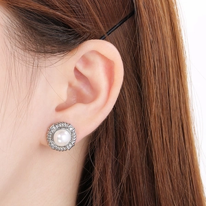 Close-up of a textured silver stainless steel earring with a pearl on an ear
