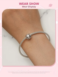 Mesh silver bracelet featuring a hollow floral charm worn on a female wrist