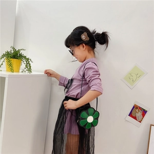 Detail shot of a cute green flower-shaped crossbody bag styled with a purple top and tutu