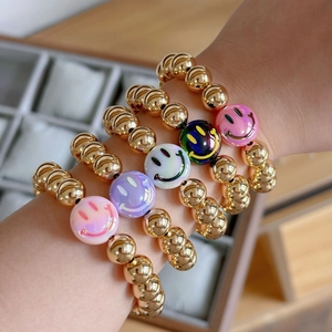 Set of 5 gold-plated beaded bracelets with colorful smiley faces worn on a wrist