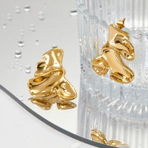 Polished gold 316L stainless steel wavy geometric earrings on reflective mirror